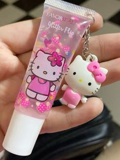 a hello kitty keychain is holding a lip bale