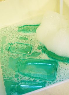 soapy water in a bathtub filled with green bottles