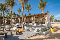 an outdoor seating area on the beach with palm trees