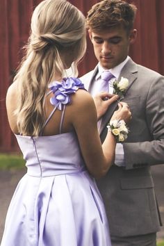 a man in a suit and tie adjusting the flower on his bridesmaid's dress