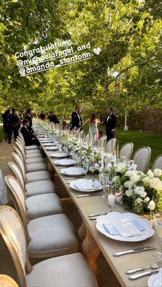 the long table is set with white flowers and place settings for an outdoor wedding reception