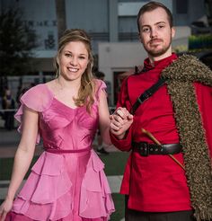 a man and woman dressed up in costume posing for a photo with one holding the other's hand