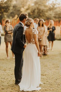 a bride and groom standing next to each other in front of a group of people