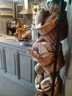 breads and pastries are stacked in baskets on the counter