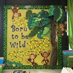 a bulletin board with bananas and monkeys on it that says born to be wild in front of a tree