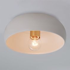 a light that is on the ceiling with a white wall in front of it and an object behind it