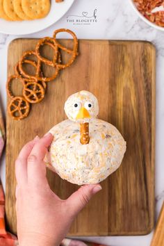 a person holding a pretzel shaped like a turkey on top of a cutting board