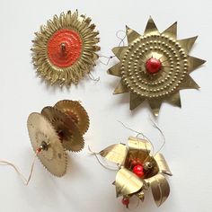 three different types of ornaments are hanging on the wall, one red and one gold