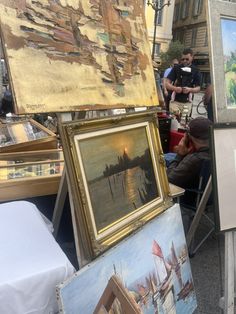 people looking at paintings on display in an outdoor market