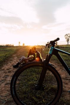 a person laying on the ground next to a bike with the sun setting in the background