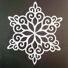 a paper snowflake cut out on a black surface with white swirls in the center