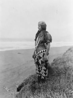 an old black and white photo of a person standing on a hill overlooking the ocean