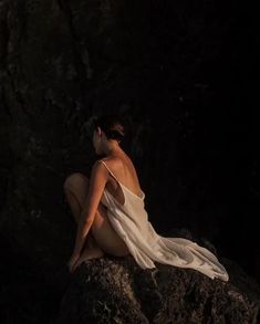 a woman sitting on top of a rock in the dark