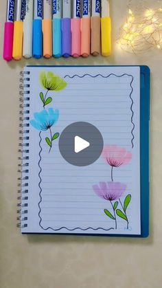 an open notebook with markers and crayons next to it