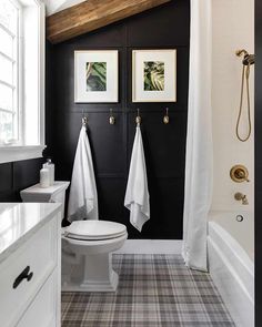 a white toilet sitting next to a bath tub in a bathroom under a wooden beam