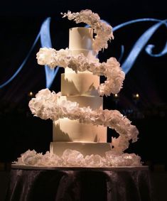 a wedding cake with white frosting and flowers on the top tier is lit by blue lights