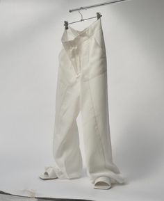 a pair of white pants hanging on a clothes line with one leg in the air