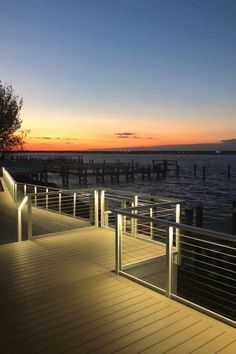 the sun is setting over the water and there are some lights on the boardwalks