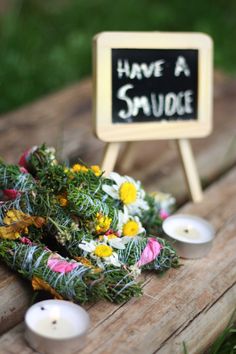 flowers and candles on a wooden table with a sign that says have a smudge