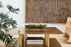 a wooden table topped with a green bowl filled with eggs next to a potted plant