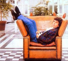 a man laying on top of a leather chair