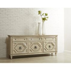 a white dresser with two vases on top of it and flowers in the bottom