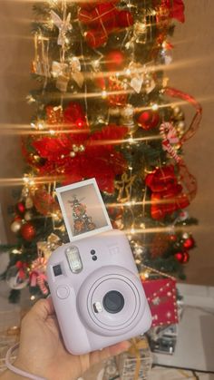 a person holding up a camera in front of a christmas tree