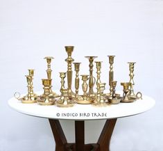 a white table topped with lots of gold cups and vases on top of it