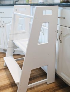 a white step stool sitting on top of a wooden floor next to a kitchen counter