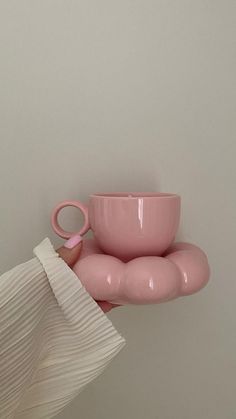 a person holding a pink coffee cup and saucer