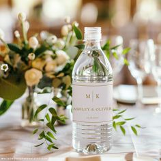 a bottle of water sitting on top of a table next to flowers and wine glasses