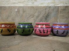 four colorful bowls with designs on them sitting in front of a marble wall