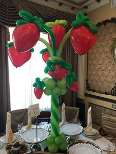 a table set with plates, silverware and balloons in the shape of strawberries