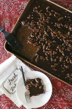 a piece of chocolate cake on a plate next to a fork and napkin with a spoon in it