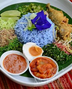 a white plate topped with rice, meat and veggies next to sauces