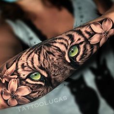 a tiger with green eyes and flowers on his arm