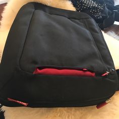 a black backpack with red zippers sitting on top of a white fur covered floor