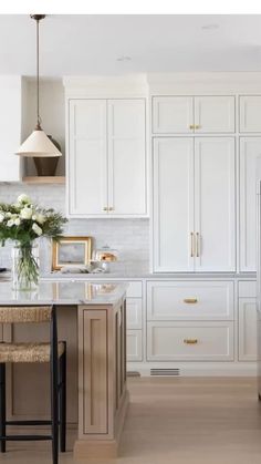 a kitchen with white cabinets and an island in front of the sink, along with two stools