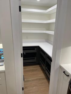 an empty kitchen with white cabinets and black appliances on the counter top, in front of a laptop computer