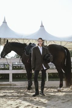 a woman standing next to a brown horse