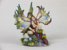 a figurine of a fairy sitting on top of a tree stump holding a bird