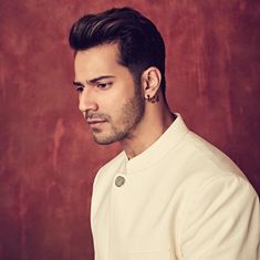 a man with ear piercings on his ears looking off to the side in front of a red wall