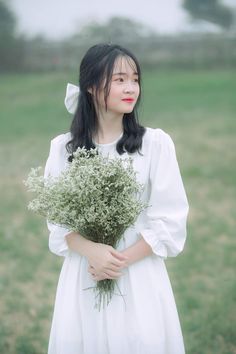 a woman in a white dress holding a bouquet of flowers