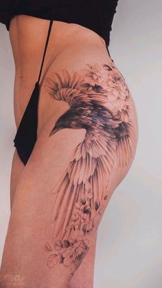 a woman's thigh with a bird tattoo on the side and flowers all over it