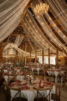 the inside of a barn with tables and chairs set up for an elegant wedding reception