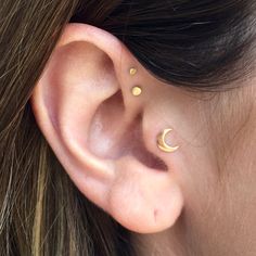 a close up of a person's ear with two small gold dots on it