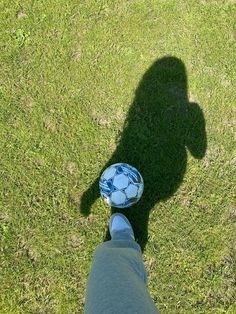 a person standing in the grass with a soccer ball on their feet, looking down