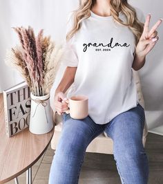 Grandma Est. 2024 Shirt! Celebrate the exciting arrival of a new generation with our Grandma Est. 2024 shirt! This soft and stylish tee is the perfect way to honor a first-time or soon-to-be grandmother. Whether you're announcing the big news or simply enjoying your new title, this shirt is a thoughtful and meaningful keepsake for any proud grandma-to-be. ♥PRODUCTION TIME: 1-5 days (Usually 2-3 days) ♥SHIPPING TIME: 2-5 days (Usually 3 days) ♥PRODUCT DESCRIPTION: Bella Canvas Unisex T-shirt Supe Grandma Pregnancy Announcement, Cute Grandma, Cute Christmas Sweater, Aunt Shirt, Announcement Pregnancy, Auntie Shirts, Aunt Shirts, Grandma Shirt, Pregnancy Announcement Shirt