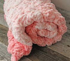 a pink crocheted blanket laying on top of a wooden floor