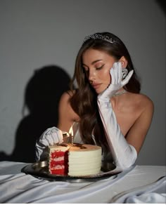 a woman in white gloves is blowing out the candles on a red and white cake